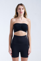 Woman wearing a black strapless top and high-waisted shorts on a white background